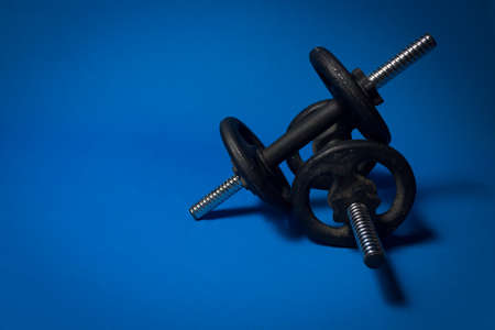 Two iron dumbbells over each other, against a blue backgroundの写真素材