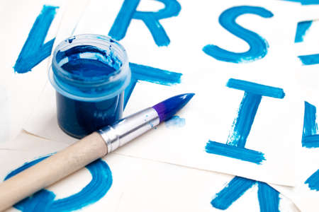 Alphabet drawing. Process of creating watercolor font. Blue gouache in the jar and brush on background with blue colored letters.の写真素材