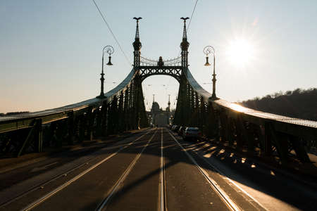 Budapest, Hungary - March 08, 2017: Street view of carriageway and tram rails on Liberty Bridge on sunset, connects Buda and Pest across the river Danubeのeditorial素材