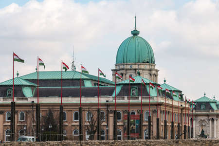 Budapest, Hungary - March 09, 2017: National hungarian waving flags in front of Royal palace building in Buda castleのeditorial素材