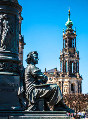 Ernst Friedrich August Rietschel statue detail symbolizing drawing. Bronze sculpture of sitting man and Cathedral of the Holy Trinity or Hofkirche on the background. Landmarks of Dresden, Germanyの写真素材