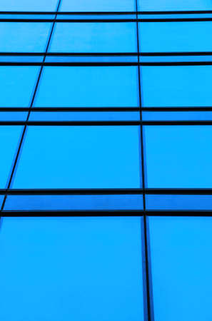 Low angle on glass facades of modern skyscraper in sunny day. Concept of business background with architecture details of financial district buildingの写真素材