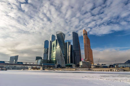 Skyscrapers of Moscow city business center in winter, frozen Moscow river and blue sky with clouds.