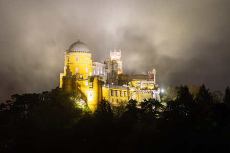 Illuminated Pena Palace in Sintra at Night. Portugal. Clouds, Fog.の写真素材