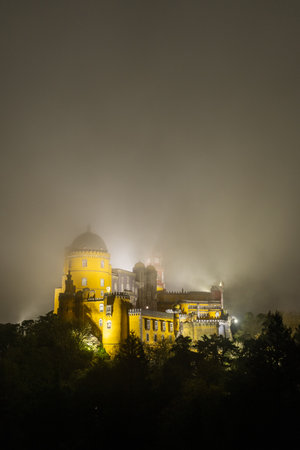 Illuminated Pena Palace in Sintra at Night. Portugal. Clouds, Fog.の写真素材