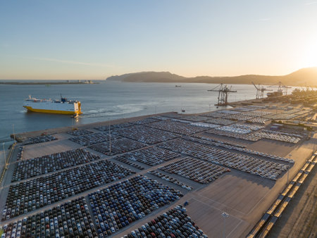 RORO Cargo Ship and New Cars on Large Full Parking Lot at Sunset in Port Ready for Distribution. Car...