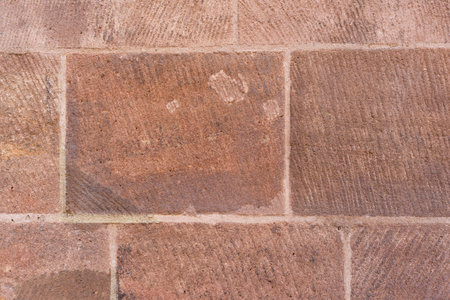 red sandstone brick wall texture. rectangular blocks, rough, weathered, visible tooling marksの写真素材