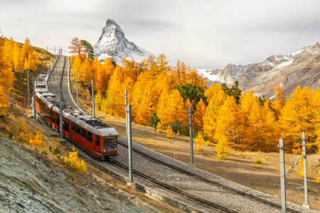 Red Train on Cog Railway, Matterhorn Mountain and Yellow Golden Larches in Autumn. Fall Colors. Swiss Alps. Zermatt, Valais, Switzerlandの写真素材
