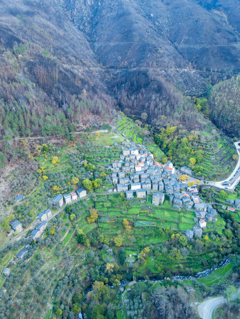 Piodao historic schist village in autumn and Serra do Acor mountain slope with lush green and burned...