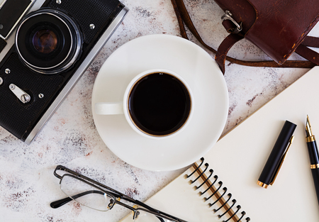 Flat lay, top view office table desk. Desk workspace with retro camera, diary, pen, glasses, case, cup of coffee on white background.の写真素材