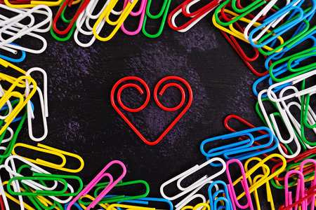 Colored paper clips isolated on dark backgroundの写真素材
