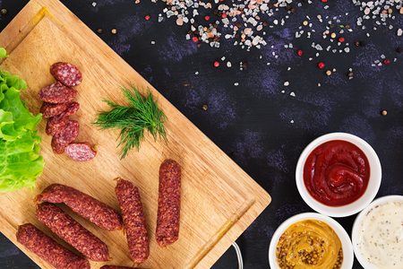 Smoked sausages with spices on dark background. Top viewの写真素材