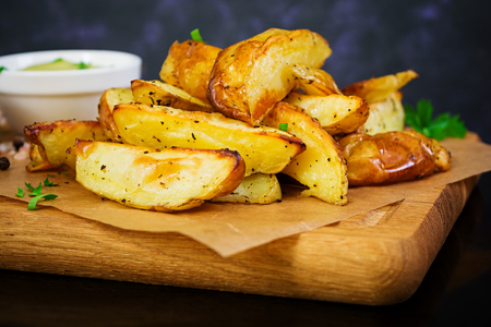 Baked potato with sauce and spices on dark backgroundの写真素材