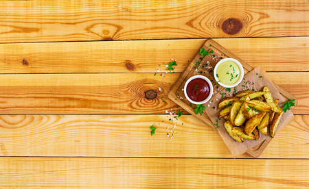 Baked potato with sauce and spices on dark background