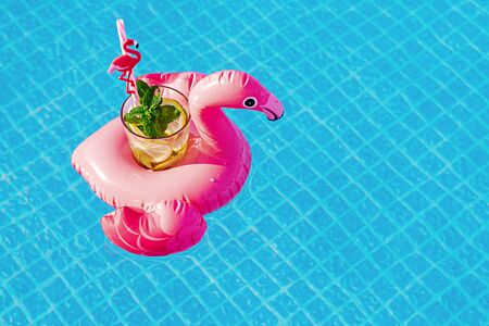 Fresh cocktail mojito on inflatable pink flamingo toy at swimming pool. Vacation concept.の写真素材