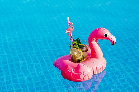 Fresh cocktail mojito on inflatable pink flamingo toy at swimming pool. Vacation concept.の写真素材