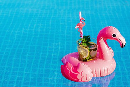 Fresh cocktail mojito on inflatable pink flamingo toy at swimming pool. Vacation concept.の写真素材
