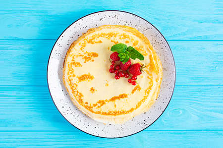 Pancakes with caramelized apples, raspberries, strawberries and red currants. Brunch with green tea and crepes.の写真素材