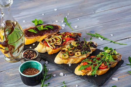 Bruschetta with chicken liver paste. Delicious bruschettas with various fillings. Different bruschetta ob wooden backgroundの写真素材