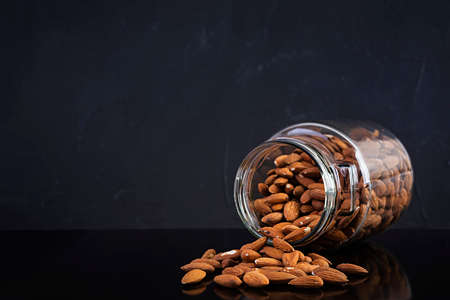 Almonds nuts in a jar. Set of nuts isolated on dark backgroundの写真素材