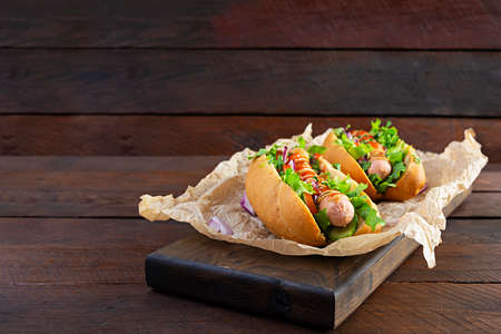 Homemade hot dog with sausage, salad, carrot, cucumber and tomato on wooden backgroundの写真素材