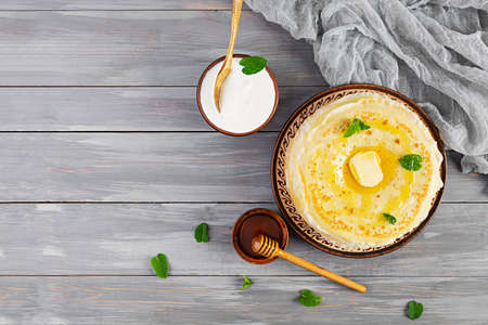 Delicious crepes with honey and sour cream on wooden background