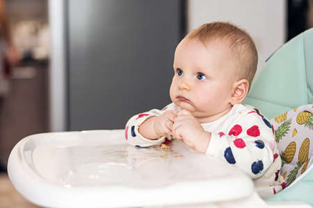 Little baby eating sitting on a child chair. Cute baby eats