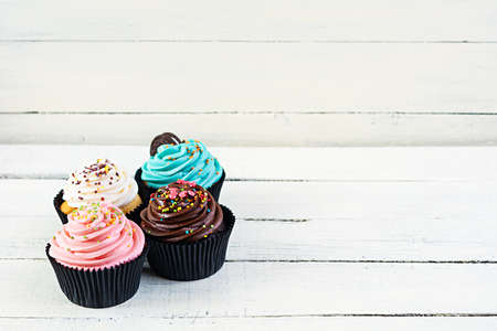 Tasty colorful cupcakes isolated on wooden background. Delicious cupcake
