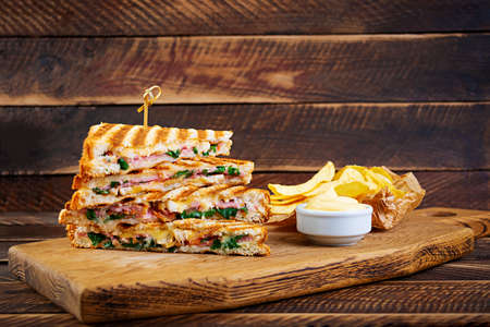 Club sandwich with ham, cheese, tomato, salad and chipsの写真素材