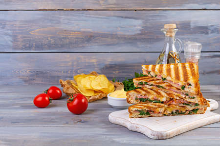 Club sandwich with ham, cheese, tomato, salad and chips