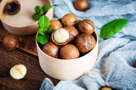 Macadamia nuts in shell with mint leaves and honey on wooden backgroundの写真素材
