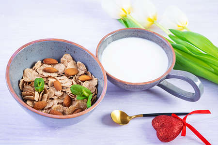 Spelt flakes with milk on breakfast. Light breakfast on Valentine's day with tulips and heart