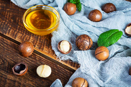 Macadamia nuts in shell with mint leaves and honey on wooden backgroundの写真素材