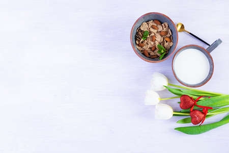 Spelt flakes with milk on breakfast. Light breakfast on Valentine's day with tulips and heartの写真素材