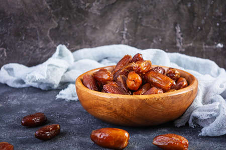 Dried date fruit in bowl on wooden background. Delicious dates fruitの写真素材