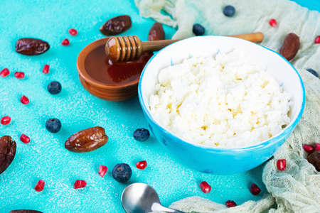 Cottage cheese with honey and berries on blue background. Light vegetarian breakfast
