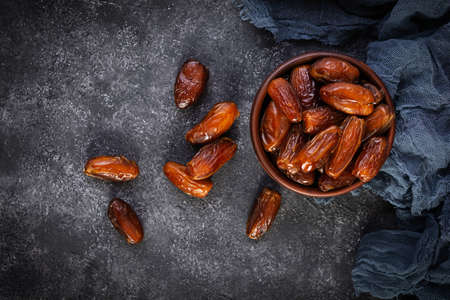 Dried date fruit in bowl on wooden background. Delicious dates fruit. Top viewの写真素材