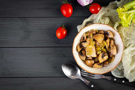 Stew chicken thighs with mushrooms, celery, onion and pepper. Stir fry chicken on wooden backgroundの写真素材