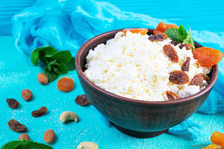Healthy breakfast cottage cheese with raisins, dried apricots, almond, cashew and mintの写真素材