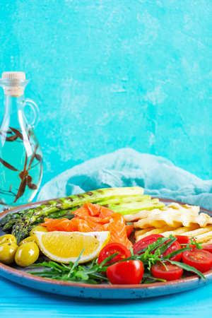 Salad with asparagus, grilled halloumi cheese, salmon fillet, tomatoes, arugula and green olivesの写真素材