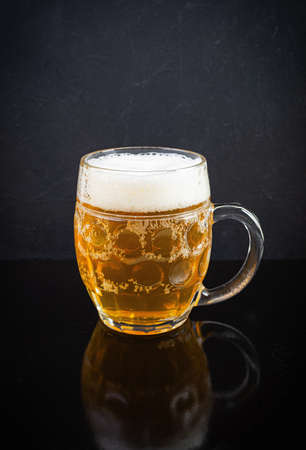 Mug of light beer on dark background. Craft unfiltered beerの写真素材