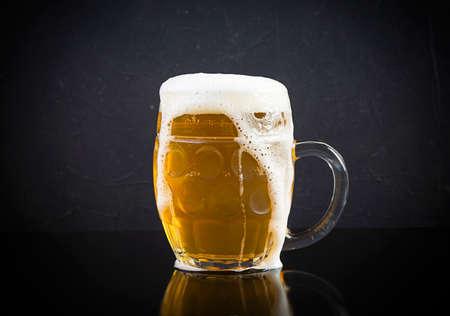 Mug of light beer on dark background. Craft unfiltered beer