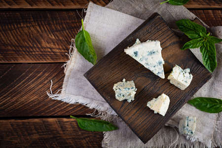 Sliced blue cheese on wooden background. Tasty dorblue on cutting boardの写真素材