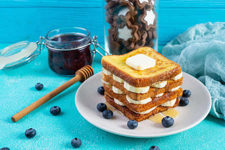 French toast with banana, blueberry, honey and strawberry jam. Delicious morning breakfast or brunch with toast and cookiesの写真素材