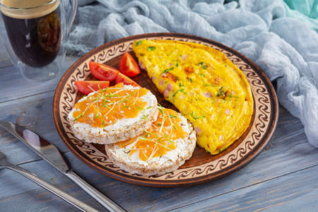 Fried omelette with beef and herbs. Delicious breakfast with eggs, puffed rice cakes and salmon