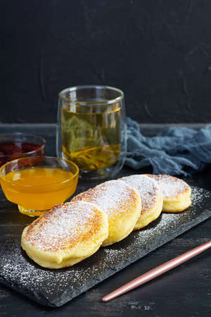 Delicious homemade syrniki with strawberry jam and honey. Traditional Russian dish syrniki