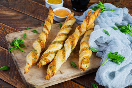 Puff sticks with cheese and herbs. Homemade breadsticks with sauce