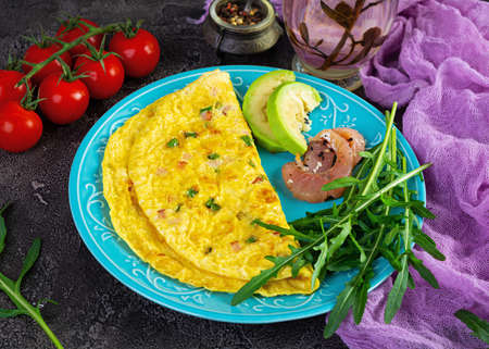 Fried omelette with ham, onion and herbs. Breakfast with scrambled eggs