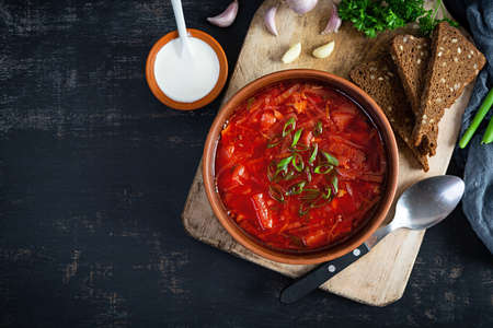 Traditional ukrainian borscht with green onion and sour cream. Delicious beet soup in bowl with rye...