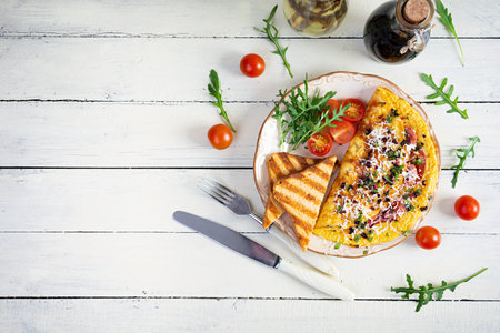Fried omelette stuffed with sausage, tomatoes, greens and cheese. Delicious easy breakfast. Top view